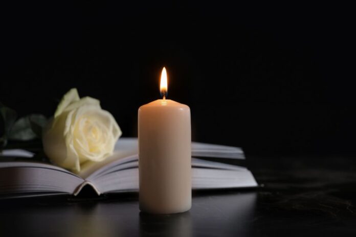 White candle in front of guest book at funeral, obituary, obituaries