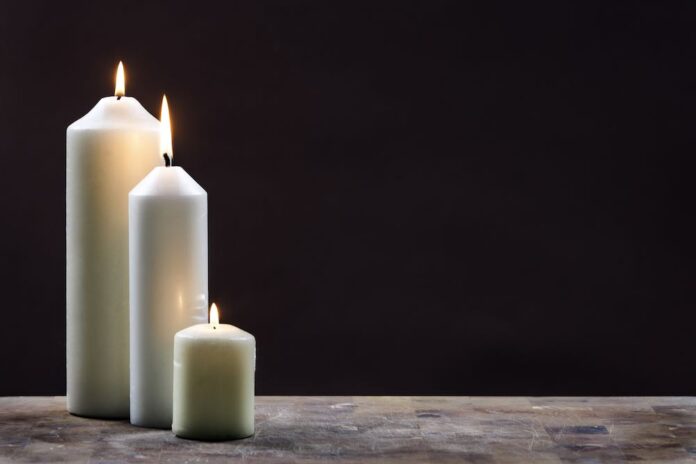 Obituary Obituaries Funeral white candles on slate countertop black background