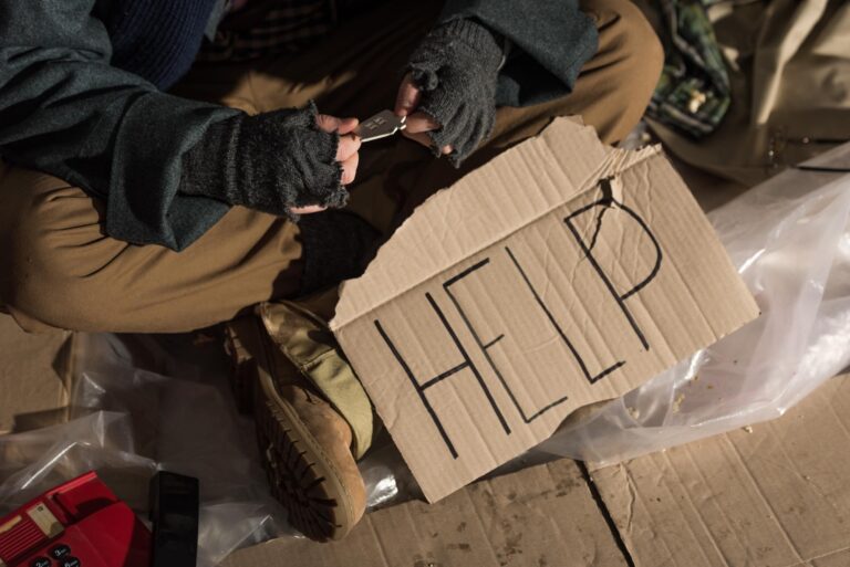 Homeless man with help sign