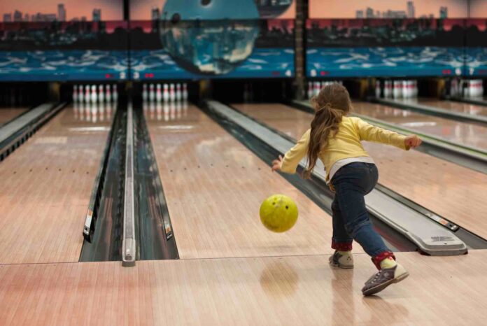 Child throwing bowling ball down lane