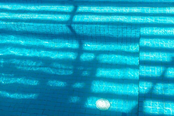 Pool bottom with tile and drain seen through the water