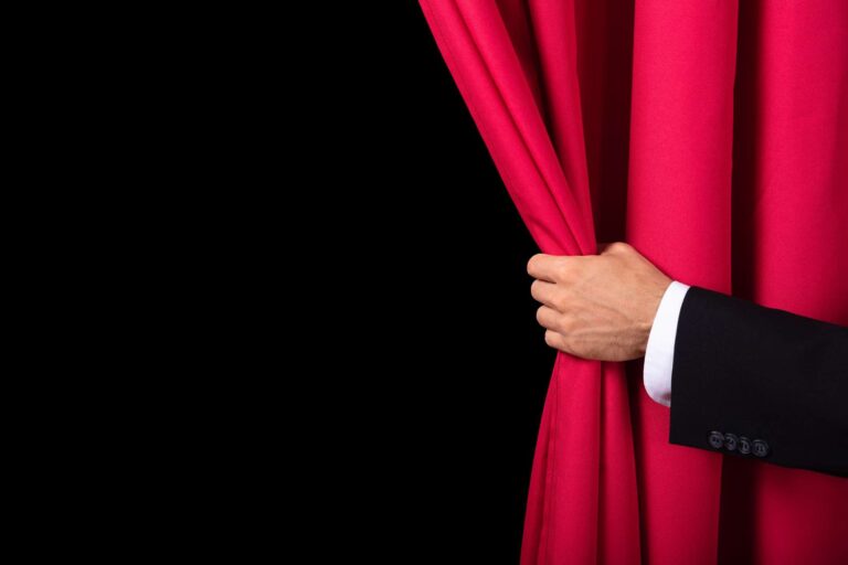 Magician opening red curtain