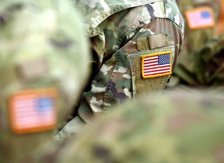 Military personnel wearing Army camouflage with American flag patch