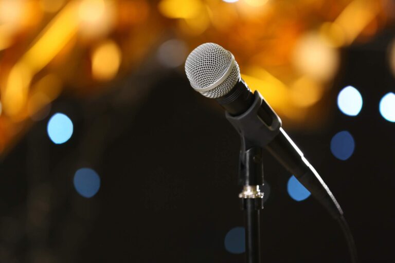 Microphone against festive lights, space for text. Musical equipment