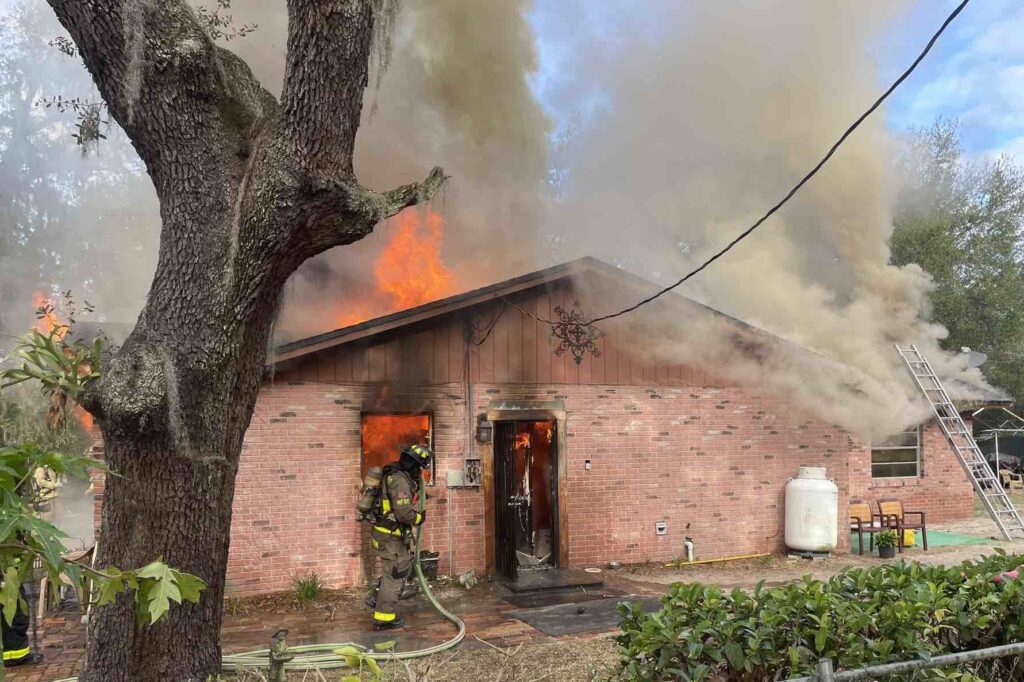 Firefigther approaches side of burning home in Maitland on February 8