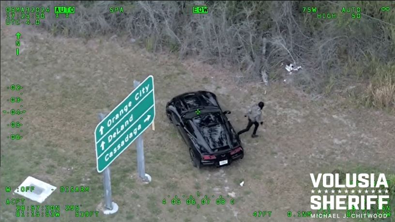 One of the armed carjacking suspects fleeing from vehicle into nearby woods on March 5, 2024